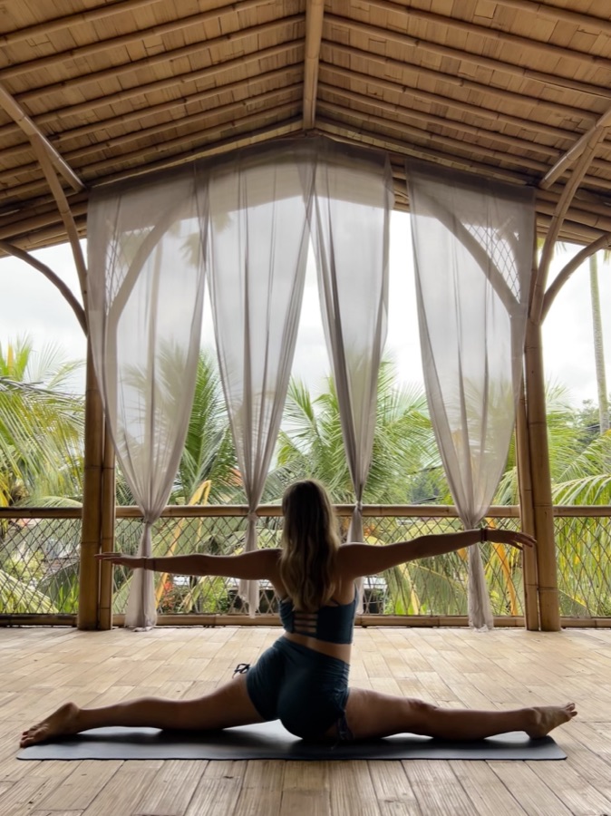 Carmen doing the splits in an open-air yoga shala